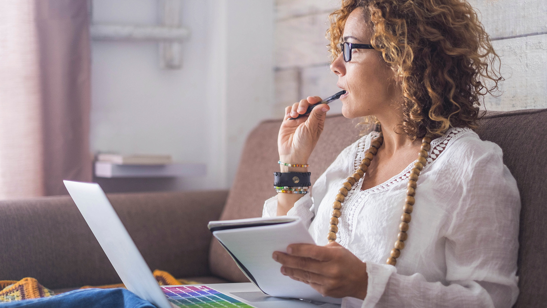 A woman holding a pen with a laptop and notepad