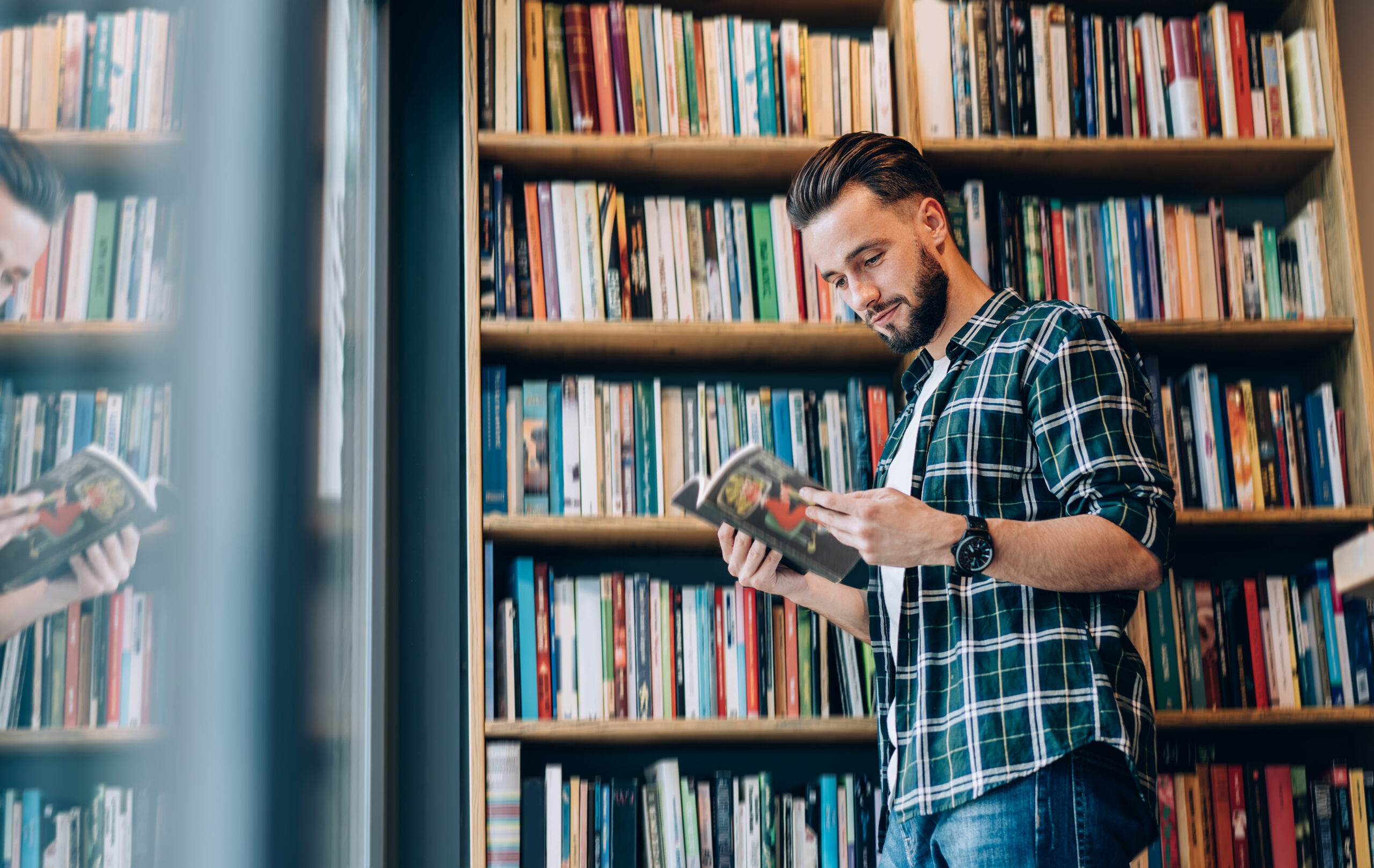 Smiling young man choosing magazine in bookstore