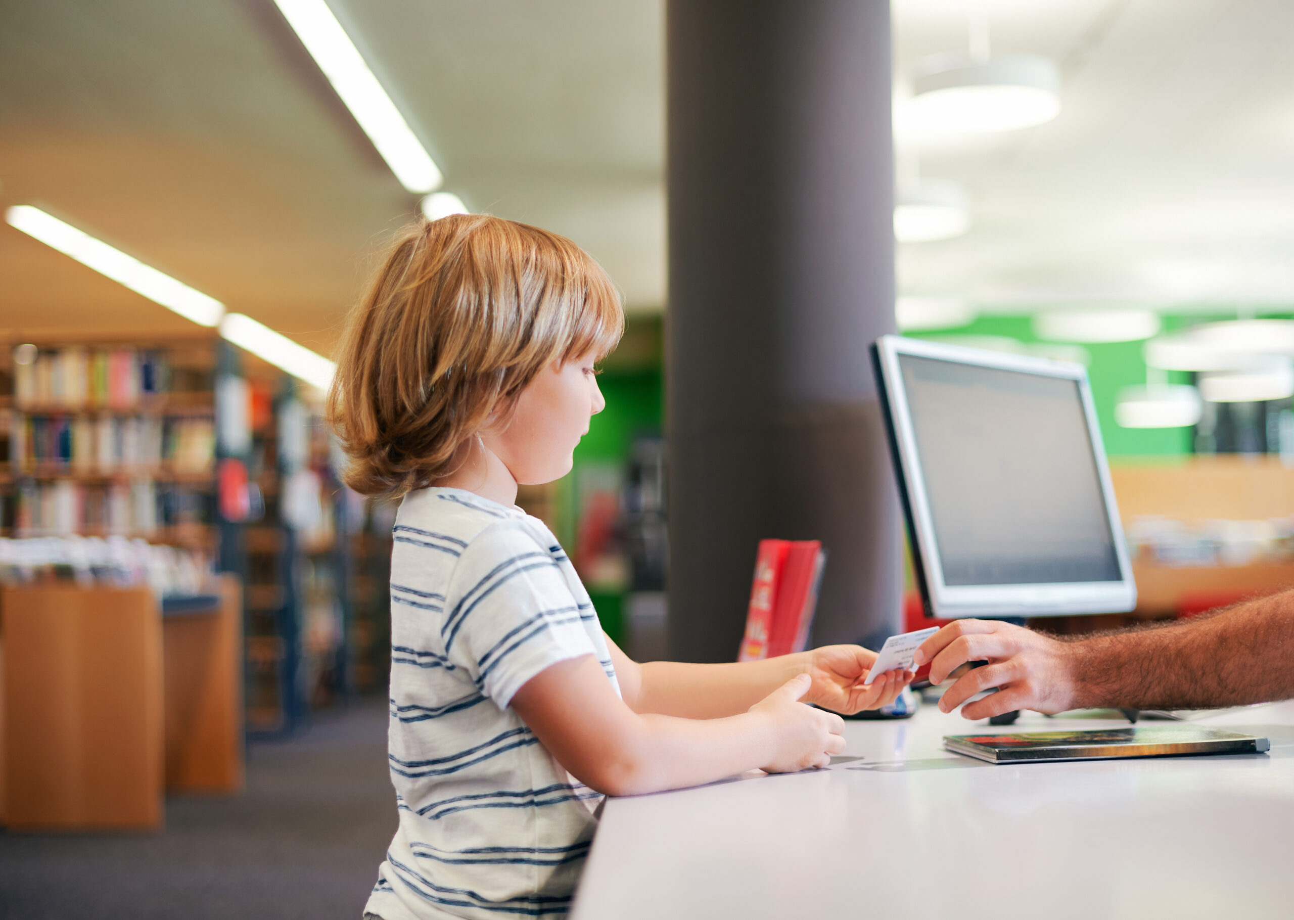 Portrait of little boy taking books in library