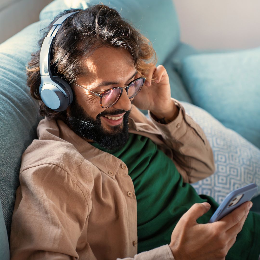 An individual sits on a couch with headphones on.