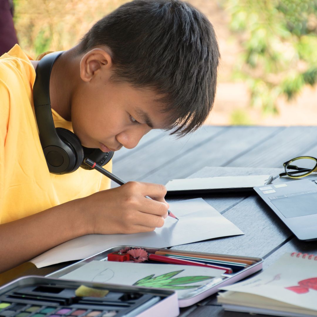 A child paints with headphones around their neck.