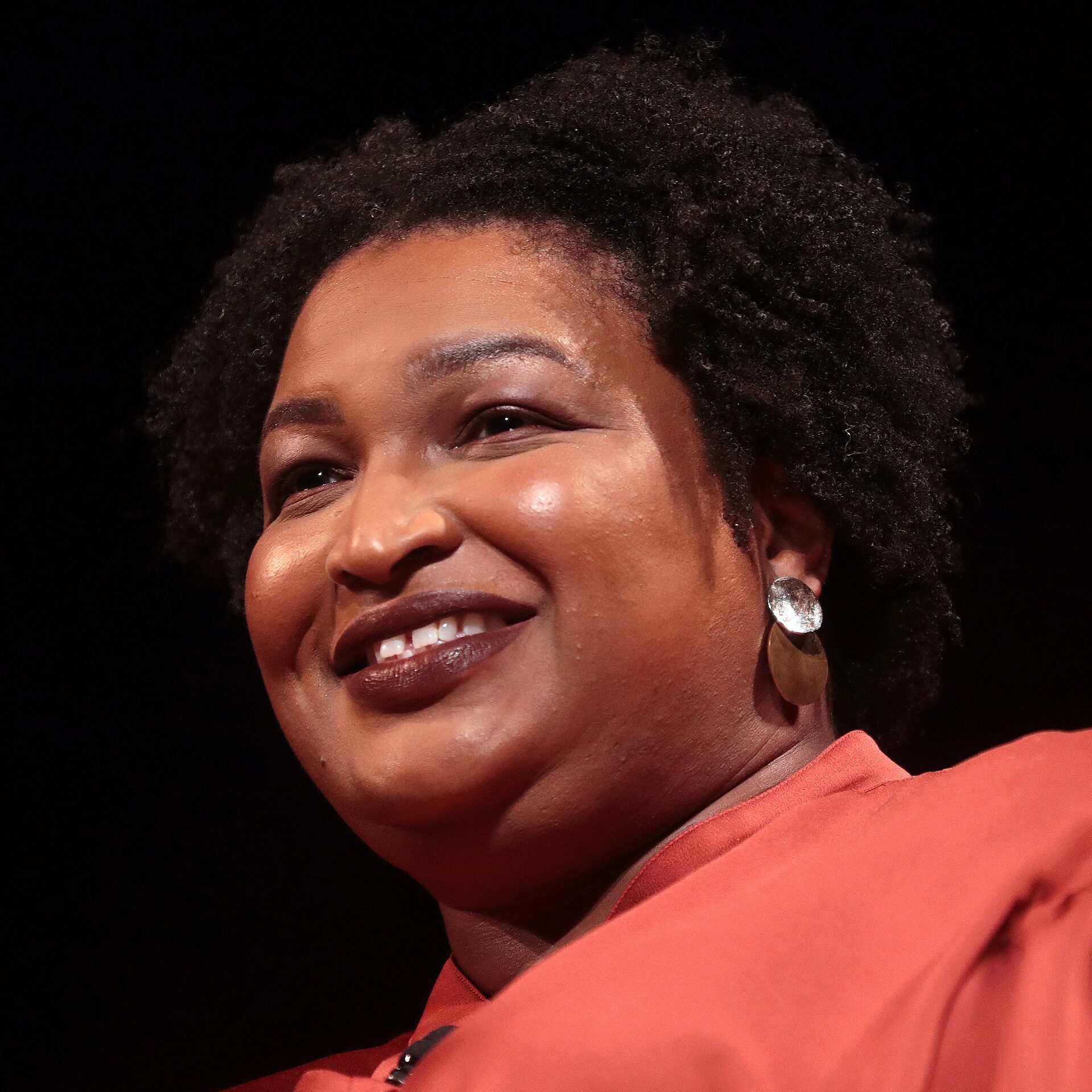 A headshot of Stacey Abrams, grinning and looking to the left.