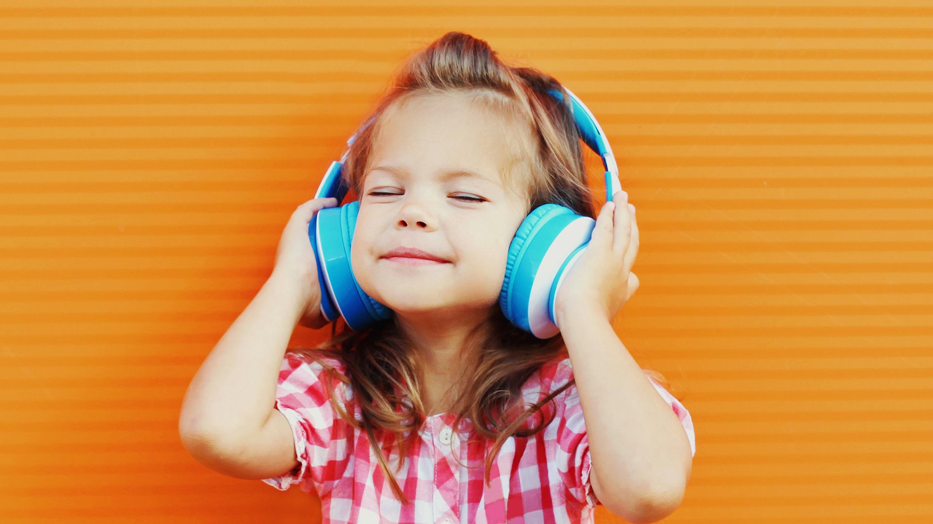 A child holds headphones over their ears