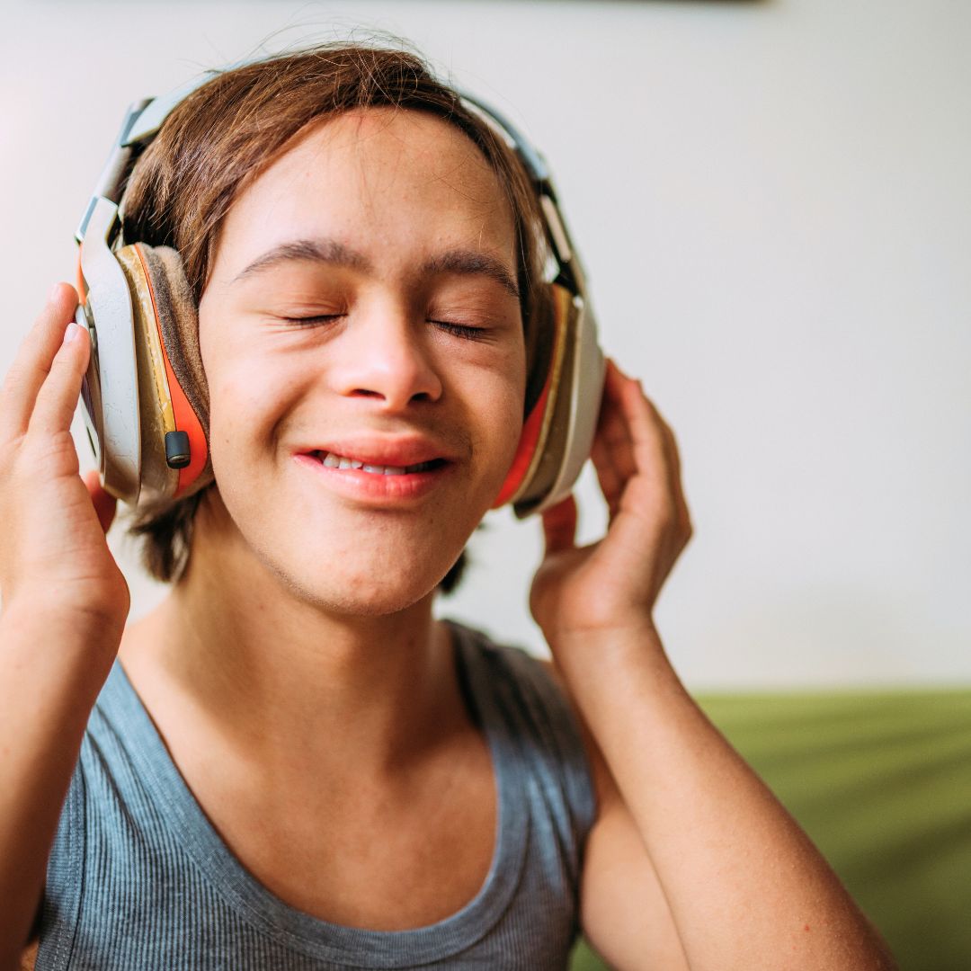 An individual has their eyes closed and holds headphones over their ears. 