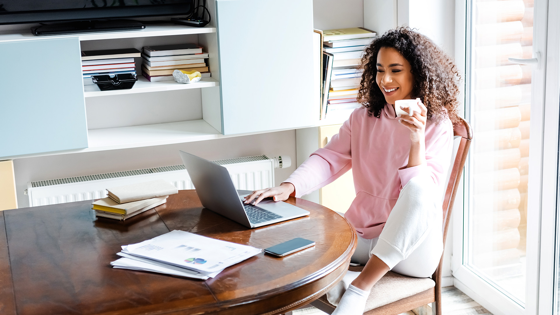 An individual at their laptop holding a mug